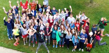 Kornerstone students and staff gathered outdoors with arms raised